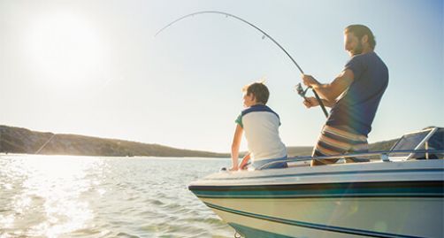 Father and son fishing from boat