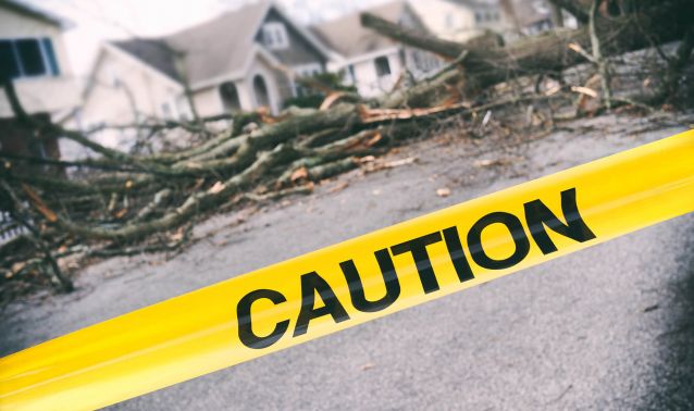 Caution tape in front of storm damage.