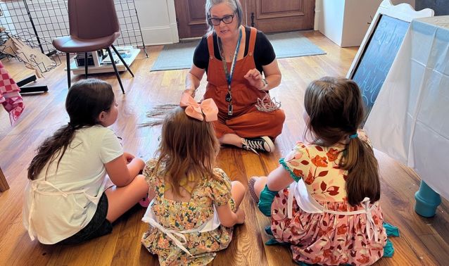 A woman instructs children on how to do art