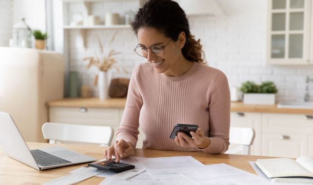 Woman using a calculator and laptop.