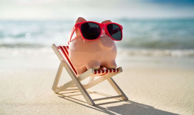 Piggybank on the beach with sunglasses.