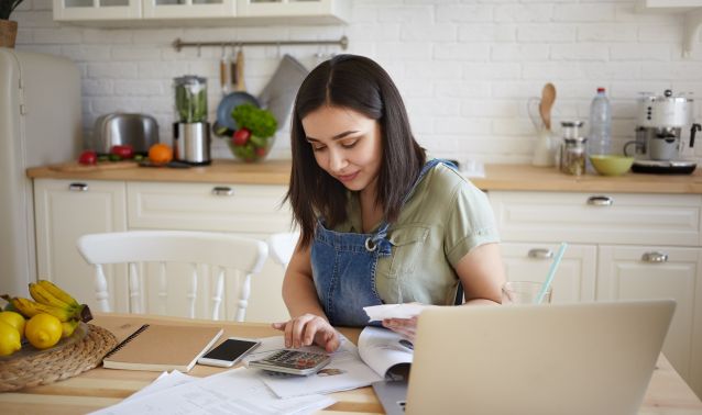 A young girl using a calculator and laptop.