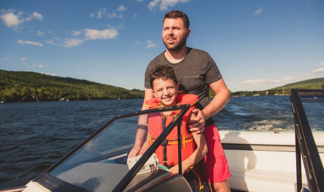 A father and son driving a boat.