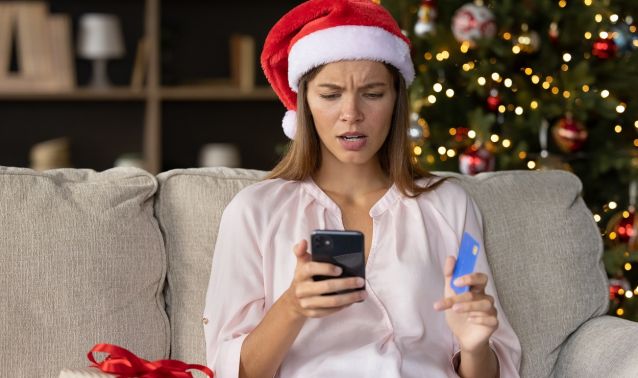 A woman looks in disbelief at her phone during the holidays.