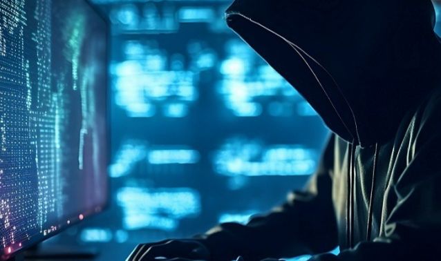 A hooded figure working on a computer.