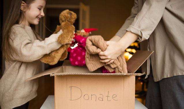 A young girl puts items in a donate box.