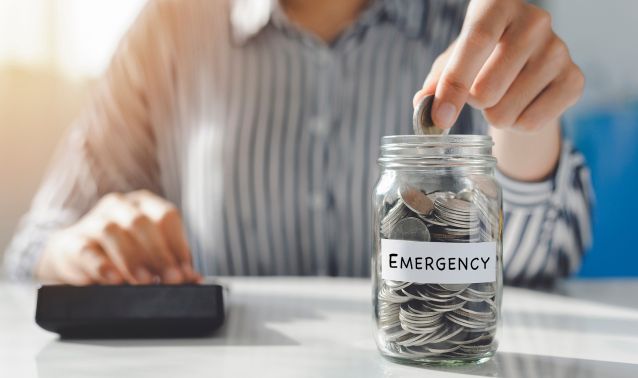 A person putting money into an emergency fund jar.