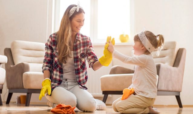 A mother and daughter high-five while spring cleaning.