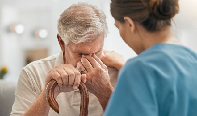 A woman comforts an elderly man who's crying.