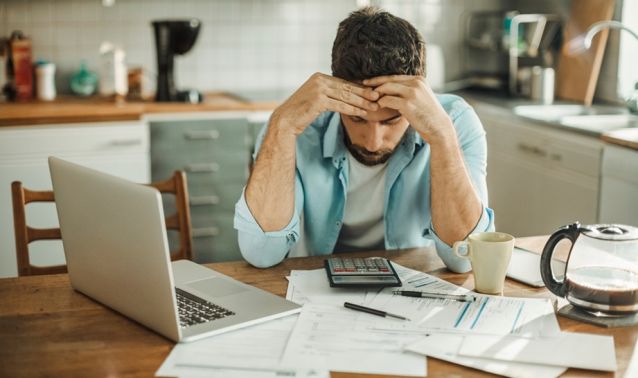 Man looks stressed while reviewing finances.