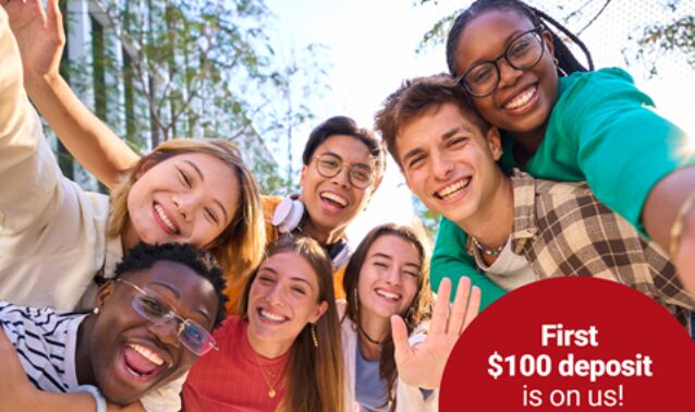 A group of teenagers gathered around in the wilderness, looking at the camera and smiling.