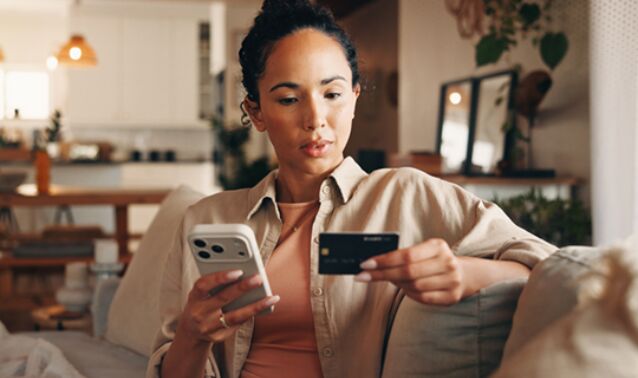 A woman looks at her banking card with concern.