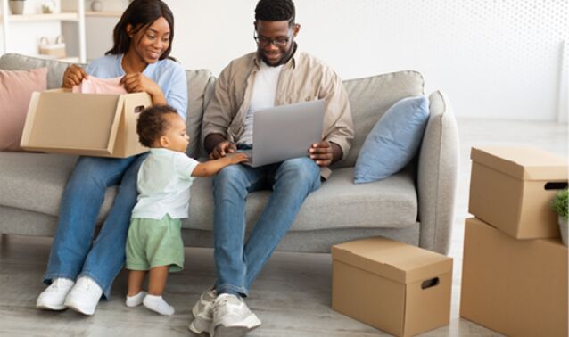 A man and woman joyfully let their child play on a laptop