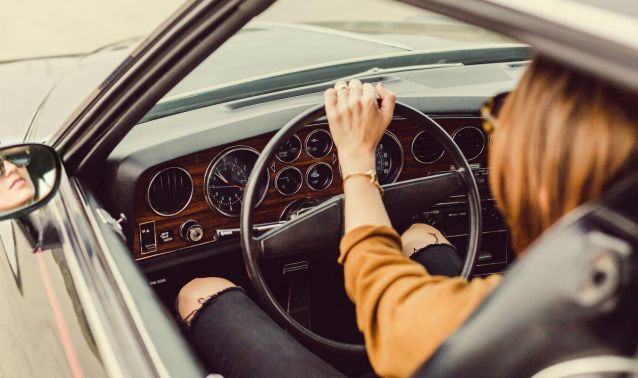 A woman driving a classic car.