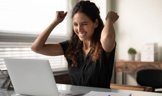 Woman excitedly looking at laptop.