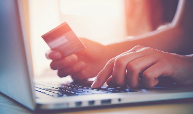 Hands using a laptop and holding a credit card.