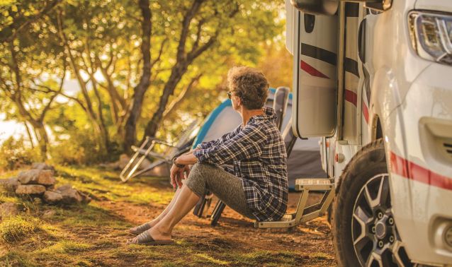 A man sits on the step of his RV.