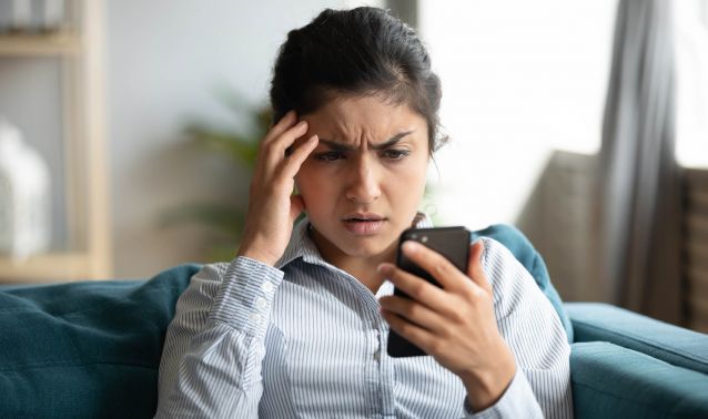 A stressed woman looking at her phone.