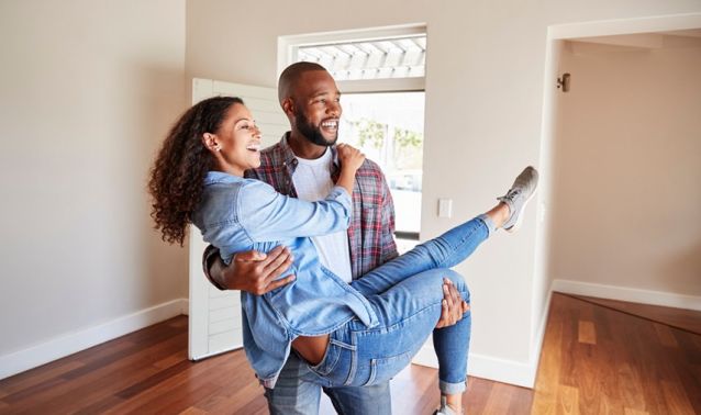 A man holds a woman in his arms as they behold their new home.