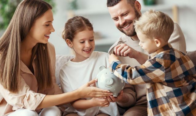 Parents with two young children putting money into piggy bank