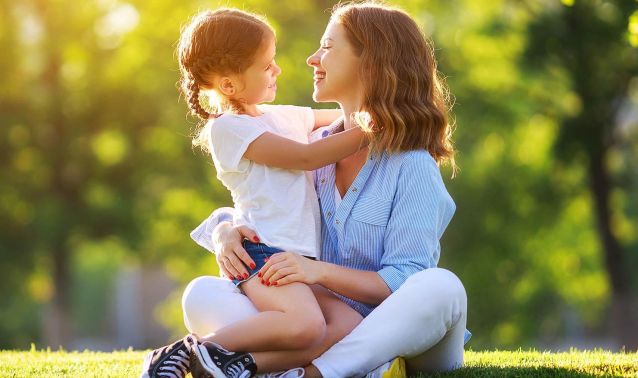 A mom and daughter hugging on a summer day.