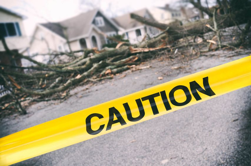 Caution tape in front of storm damage.