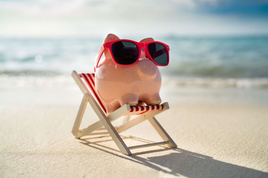 Piggybank on the beach with sunglasses.