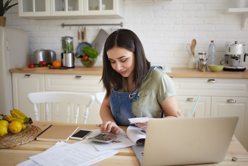 A young girl using a calculator and laptop.