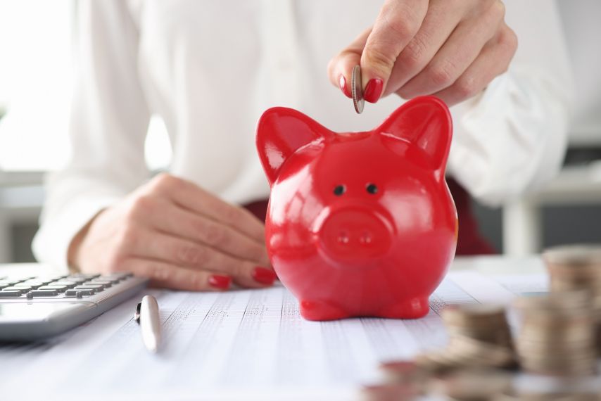 Hands putting money into a piggy bank.