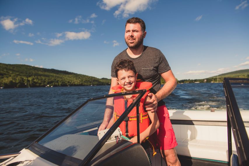 A father and son driving a boat.