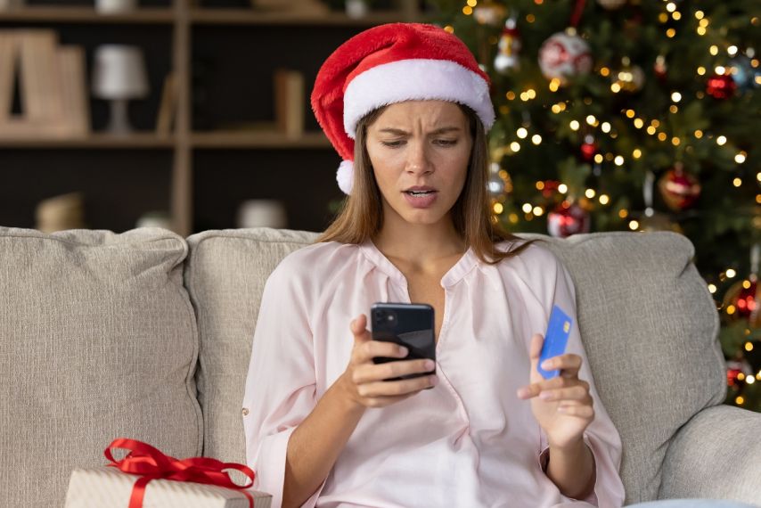 A woman looks in disbelief at her phone during the holidays.