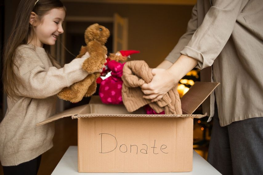 A young girl puts items in a donate box.