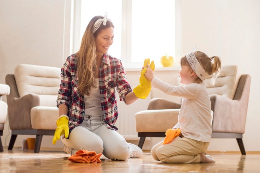 A mother and daughter high-five while spring cleaning.