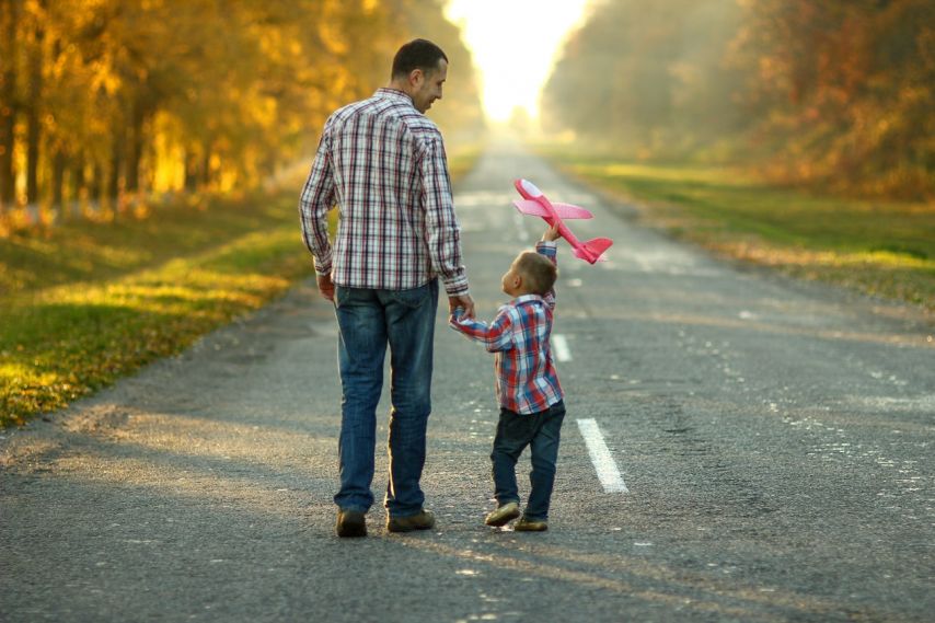 A father and son walking down a road.