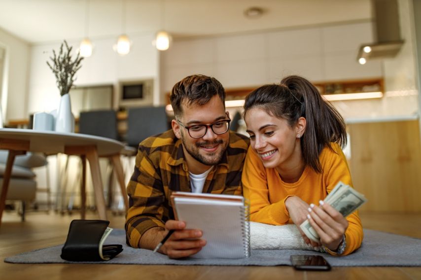 A couple laying on the floor going over their finances.