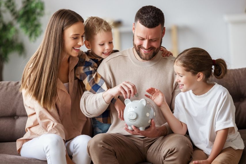 A family of four puts money into a piggybank.