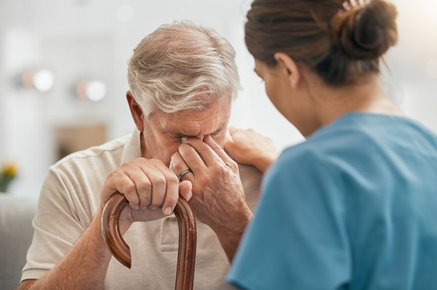 A woman comforts an elderly man who's crying.