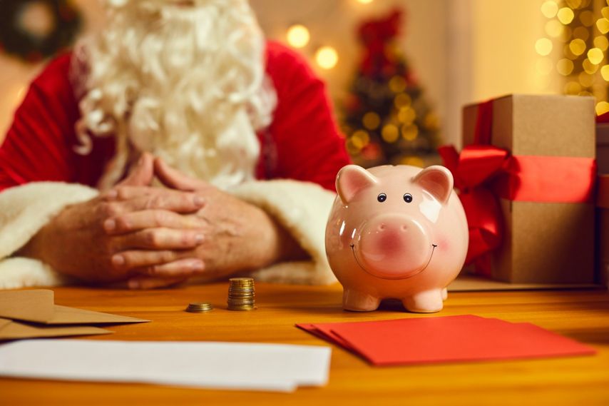 Santa sits by a piggy bank