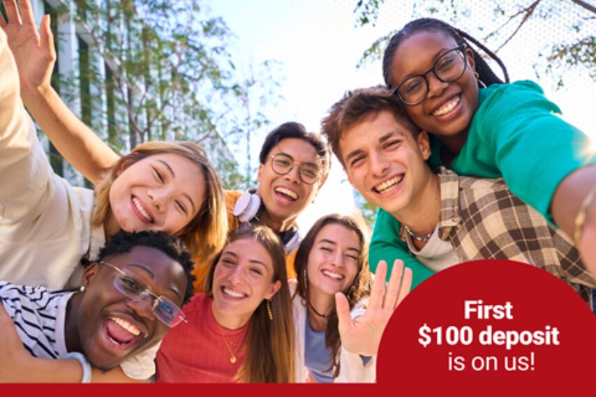 A group of teenagers gathered around in the wilderness, looking at the camera and smiling.