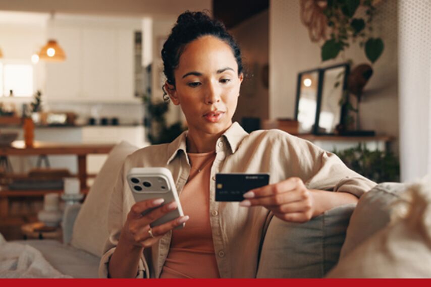 A woman looks at her banking card with concern.