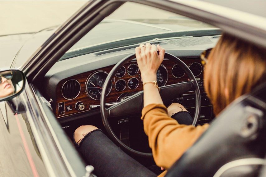 A woman driving a classic car.