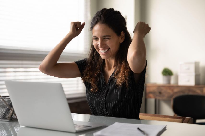 Woman excitedly looking at laptop.