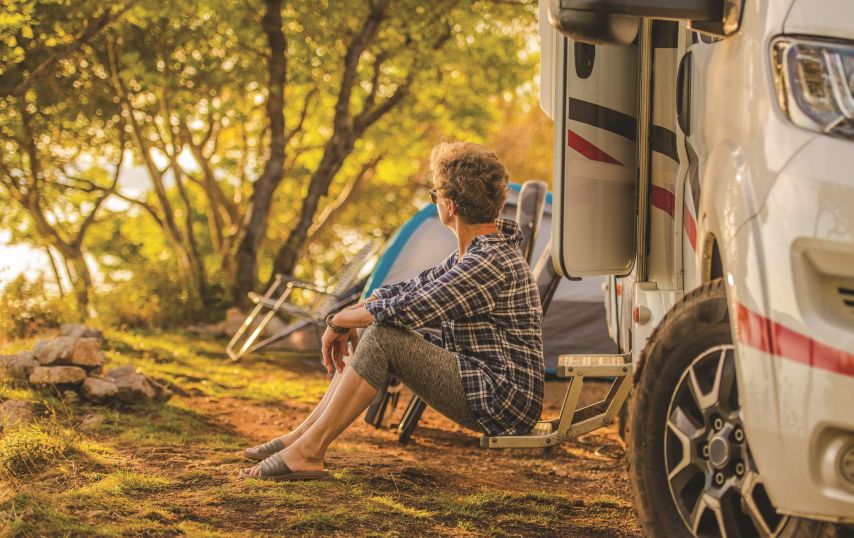 A man sits on the step of his RV.