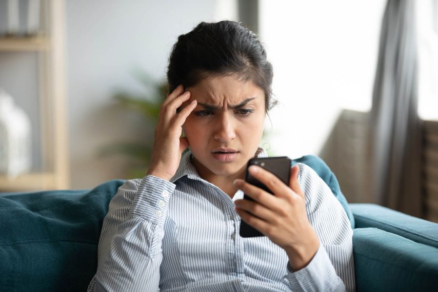 A stressed woman looking at her phone.