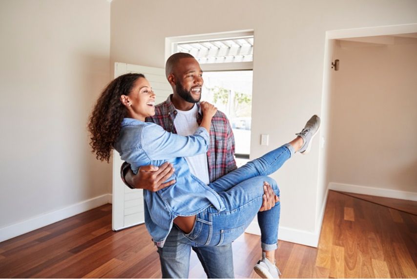 A man holds a woman in his arms as they behold their new home.