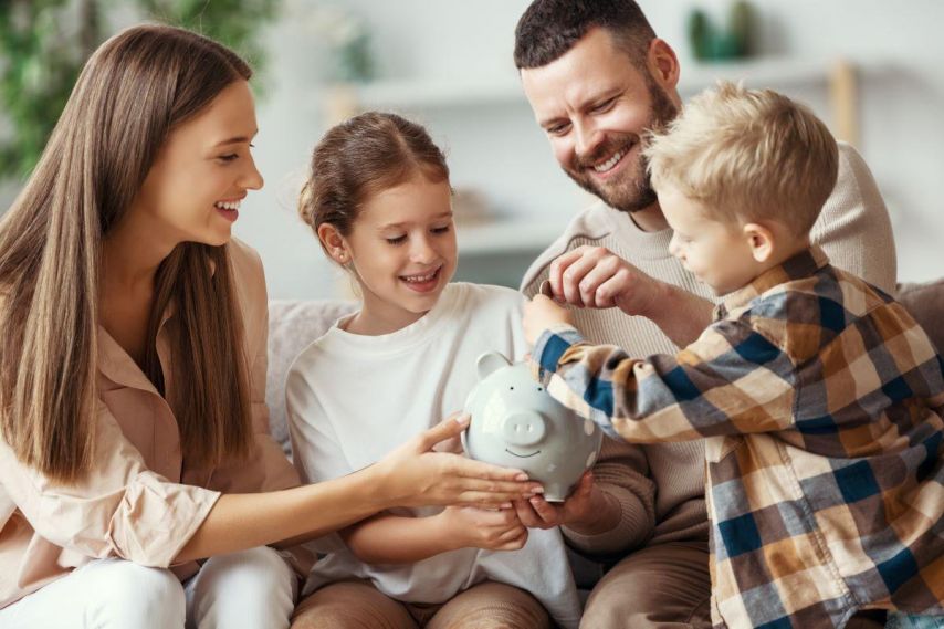 Parents with two young children putting money into piggy bank