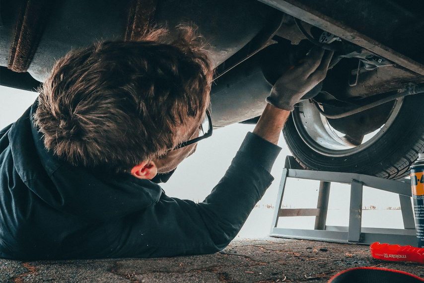 A man working on the underside of a car.