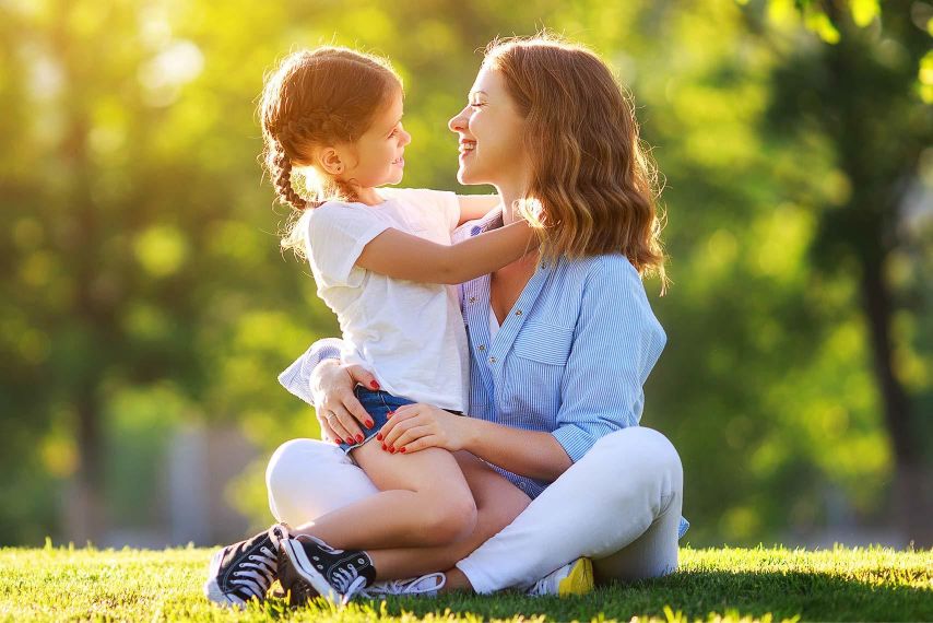 A mom and daughter hugging on a summer day.