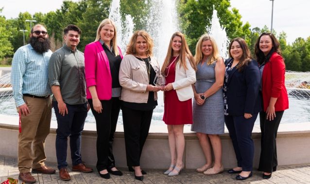 Team photo holding award in front of fountain