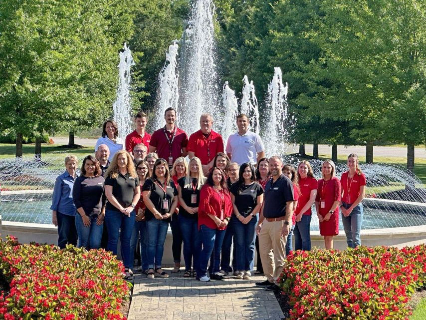 Group of employees stands in front of fountain